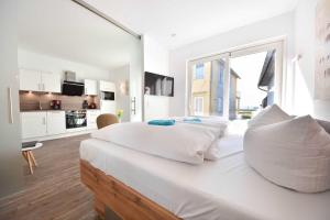 a white bedroom with a large bed with a large window at Kleines Ferienhaus Kuschelnest in Kamminke