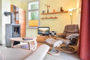 ein Wohnzimmer mit einem Kamin, einem Stuhl und einem TV in der Unterkunft (27a) Villa Seestern 05 in Heringsdorf
