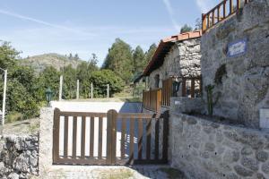 ein Tor zu einem Steingebäude mit einem Zaun in der Unterkunft Casa das Leiras in Vieira do Minho
