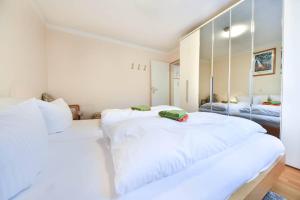 2 weiße Betten in einem Zimmer mit Spiegel in der Unterkunft Haus an der Düne Wohnung 04 in Heringsdorf