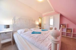 a bedroom with a large white bed with pink walls at Ferienhaus Waldhaus in Korswandt