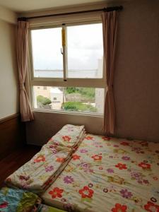 a bed in front of a window with a flower blanket at Love With Dolphin B&B in Magong