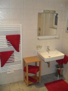 bagno con lavandino bianco e sgabello rosso di Haus Schellenschmied a Pettneu am Arlberg