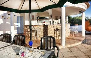 una mesa con sillas y una sombrilla en el patio en CASA BEACHCOMBER Le jardin des Arts, en Lagos