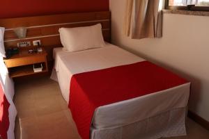 Dormitorio pequeño con cama con manta roja y blanca en Copas Executive Hotel, en Cascavel