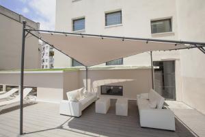 a patio with two white chairs and a fireplace at Hotel Concordia Barcelona in Barcelona