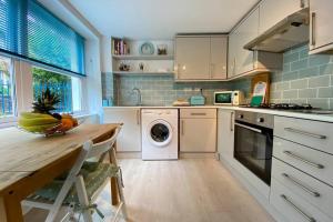 a kitchen with a table and a washing machine at Apple Cottage - Central Frome - Outdoor Space in Frome