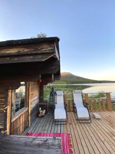 una terraza con sillas y una casa con un lago en Lake Kesänki Cottage, en Äkäslompolo