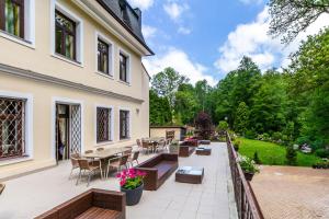 patio ze stołami i krzesłami oraz budynek w obiekcie Penzion Kokorin Forest Villa w mieście Konrádov