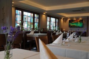 een restaurant met witte tafels, stoelen en ramen bij Hotel Eifelstube in Rodder