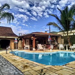 um resort com uma piscina e uma casa em Pousada Na Praia Ubatuba em Ubatuba