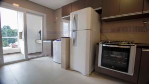 a kitchen with a white refrigerator and a window at Villa Maggiori 303 - My Home Temporada in Canela