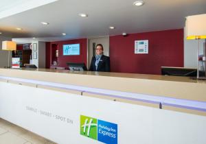 a man standing in front of a counter in a restaurant at Holiday Inn Express Exeter, an IHG Hotel in Exeter