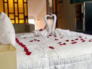 Una cama blanca con pétalos de rosa roja. en Casa Hotel Achumani, en La Paz