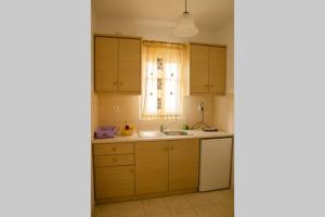 a kitchen with wooden cabinets and a sink and a window at Cycladic houses in rural surrounding 4 in Tholária