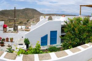 a white house with blue windows and a hill at Cycladic houses in rural surrounding 4 in Tholária