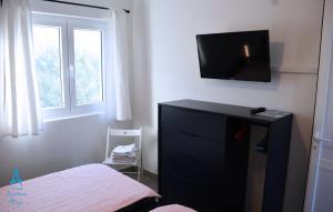 sypialnia z łóżkiem i komodą z telewizorem na ścianie w obiekcie Apartmani Prpić w Ražancu