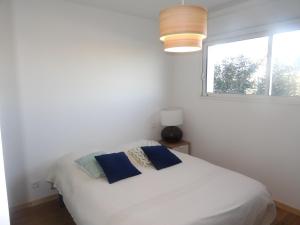 Habitación blanca con cama y ventana en Appartement neuf 6 couchages 50 metres de la plage, en Gruissan