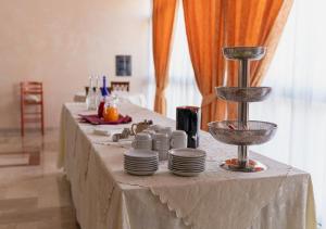 a table with plates and cups on top of it at Hotel Villa Delle Rose in Oristano