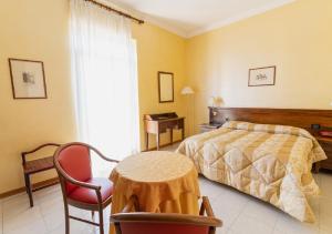 a bedroom with a bed and a table and chair at Hotel Villa Delle Rose in Oristano