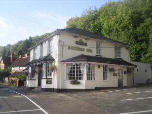 a white building with a sign that reads the pharmacy inn at The Railway Inn in Malvern Wells