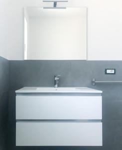 een badkamer met een witte wastafel en een spiegel bij Alba B&B in Cattolica