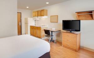 a bedroom with a bed and a desk with a television at WoodSpring Suites Grand Junction in Grand Junction