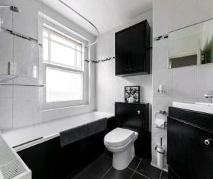 a bathroom with a toilet and a sink and a window at Highgate Maisonette with Roof Terrace in London