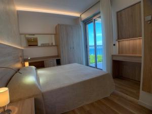 a bedroom with a large bed and a large window at Hotel Beau Rivage Pineta in Lido di Jesolo