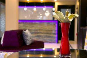 a red vase with yellow flowers on a table at Boutique Hotel Divina in Harkány