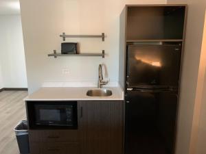 a kitchen with a sink and a black refrigerator at Studio 6 Rockford in Rockford