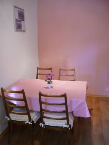une table à manger avec une nappe rose et trois chaises dans l'établissement Ferienwohnung Landwirtschaftliches Gut Taentzler, à Hecklingen