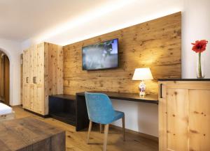 a room with a desk and a tv on a wooden wall at Hotel Garni Tirol in Ladis