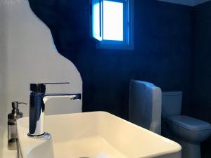 uma casa de banho com um lavatório, um WC e uma janela. em Cape Napos em Faros