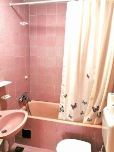 Baño de color rosa con bañera y cortina de ducha en Apartments Biočić, en Korčula