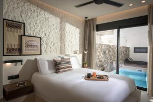 una camera da letto con un grande letto bianco e un vassoio di Tarsia Homes & Suites a Kalamaki