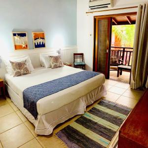 a bedroom with a large bed and a balcony at Pousada Brigitte in Barra do Sahy