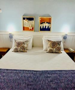 a bedroom with a large bed with four pillows at Pousada Brigitte in Barra do Sahy