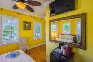 Habitación amarilla con cama y espejo. en Duval Inn - Key West, en Key West