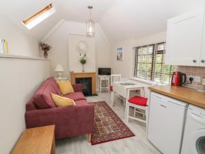 cocina y sala de estar con sofá rojo en Fir Tree Cottage, en Criccieth