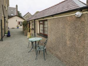 a patio with a table and chairs next to a building at Fir Tree Cottage in Criccieth