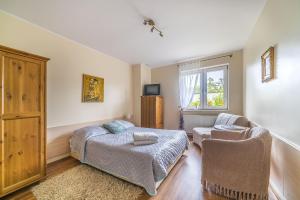 a bedroom with a bed and a chair and a window at Willa Michalinka in Jastarnia