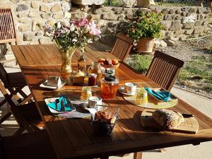 una mesa de madera con comida y flores. en L'Attrape Rêve Insolite, en Saint-Vincent-de-Barrès