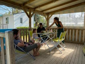 um grupo de pessoas sentadas à volta de uma mesa no convés em Camping Le Royan em Royan