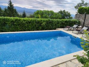 - une grande piscine bleue avec 2 chaises à côté dans l'établissement Apartment Gina, à Opatija