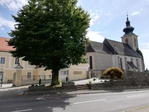 a church with a tree in front of a street at Gästehaus Reingruber in Ried im Traunkreis