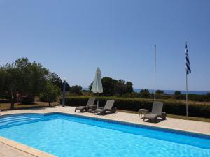 a swimming pool with two lounge chairs and an umbrella at Monambeles Villas in Svoronata