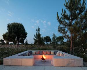 a fire burns in a fire pit with a couch at Spatia Comporta in Comporta