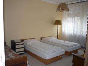 a bedroom with two beds and a lamp and a window at Zsigmond Vendeghaz in Keszthely