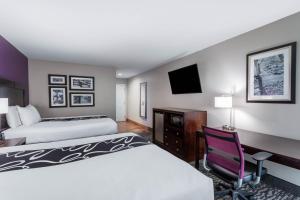 a hotel room with two beds and a desk and a chair at La Quinta by Wyndham Huntsville Airport Madison in Madison